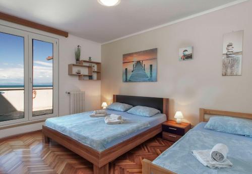 a bedroom with two beds and a large window at APARTMAJI PRI BOSI NOGI in Izola