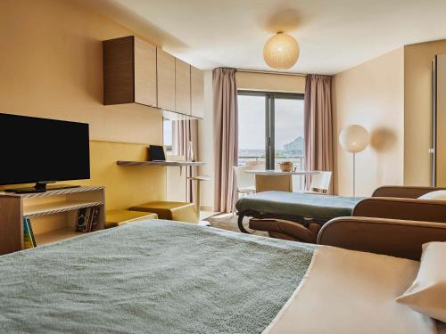 AppartHotel Mercure Paris Boulogne في بولون بيانكور: غرفة فندقية بتلفزيون وغرفة معيشة