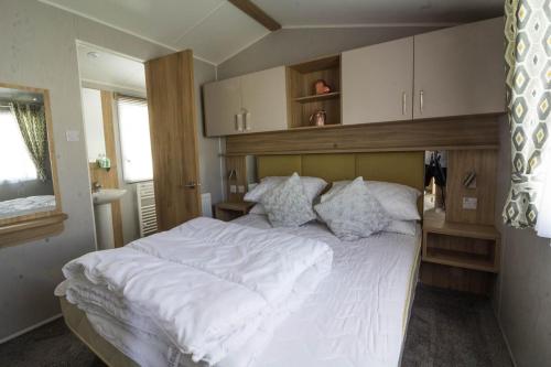 a bedroom with a large bed with white sheets and pillows at Beautiful 6 Berth Caravan At Southview Holiday Park In Skegness Ref 33031s in Skegness