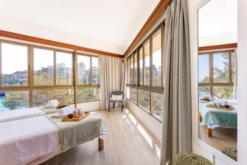 a bedroom with a bed and large windows at Apartamentos Drac in Cala Santanyi