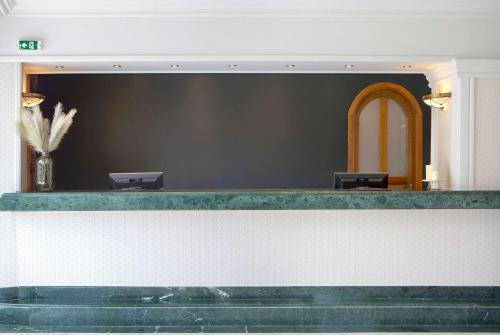 a lobby with a counter with two chairs at Ramada by Wyndham , Athens Club Attica Riviera in Mati