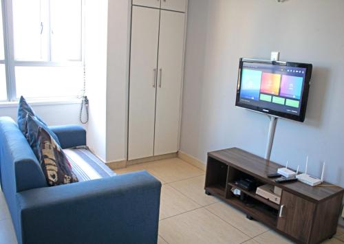 a living room with a blue couch and a tv at Unit 104 @Tenbury in Durban