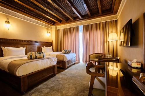 a hotel room with two beds and a table with a desk sidx sidx at Kosh Havuz boutique hotel in Samarkand