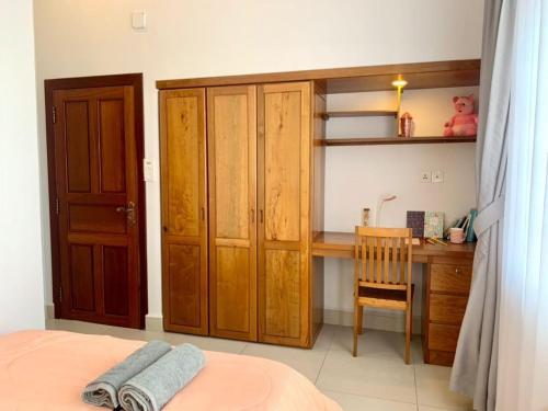 a bedroom with a desk and a bed and a wooden cabinet at Ptas Tauch Residence in Phnom Penh