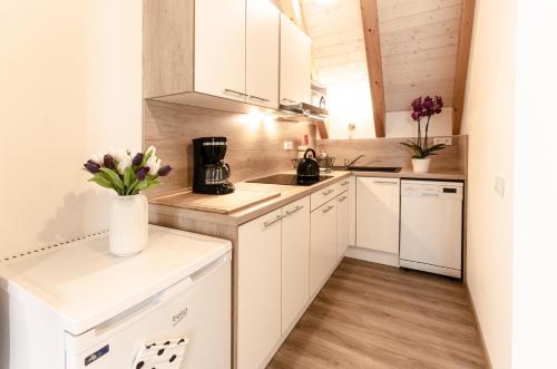 a kitchen with white cabinets and flowers in a vase at Nepomuk pod Prahou in Nepomuk