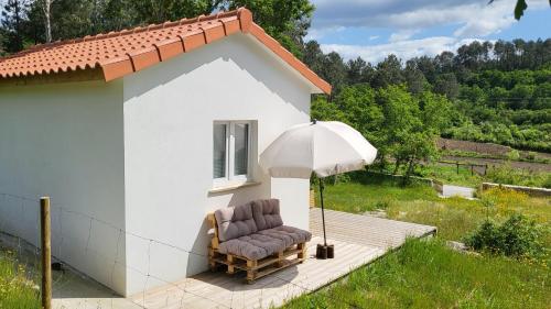 a chair and an umbrella next to a building at Casinha Rubiães in Paredes de Coura