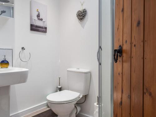 La salle de bains blanche est pourvue de toilettes et d'un lavabo. dans l'établissement The Stables, à Long Itchington