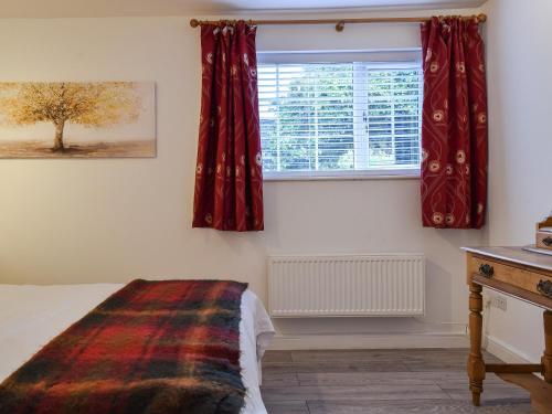 um quarto com uma cama e uma janela com cortinas vermelhas em The Stables em Long Itchington