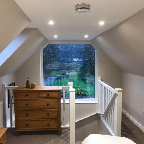 a bedroom with a large window and a dresser at Westmains Lodge in Callander