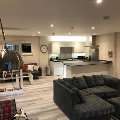 a living room with a couch and a kitchen at Westmains Lodge in Callander