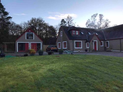 una casa con un césped verde delante de ella en Westmains Lodge, en Callander