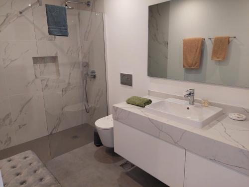 een witte badkamer met een wastafel en een douche bij Stunning Lobos View in Câmara de Lobos