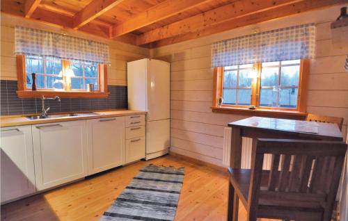 a kitchen with a refrigerator and a table and two windows at Cozy Home In Långserud With Jacuzzi in Rullan
