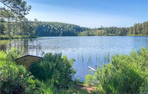 a boat sitting on the shore of a lake at Cozy Home In Långserud With Jacuzzi in Rullan