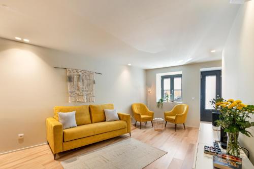 a living room with a yellow couch and chairs at São Sebastião Apartment By Sé Apartamentos in Braga