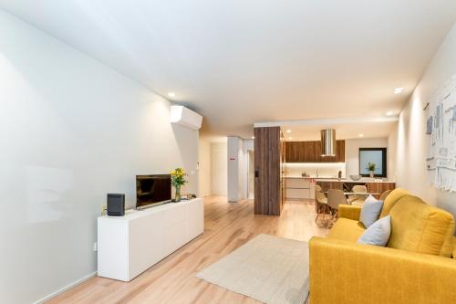 a living room with a yellow couch and a tv at São Sebastião Apartment By Sé Apartamentos in Braga