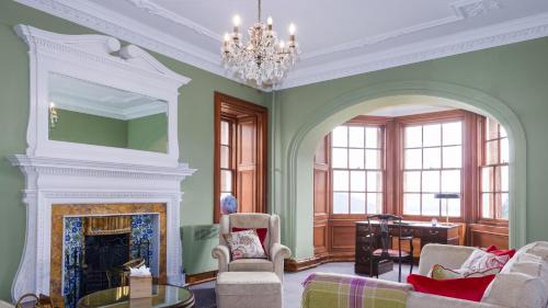 a living room with a fireplace and a chandelier at Glencoe House in Glencoe
