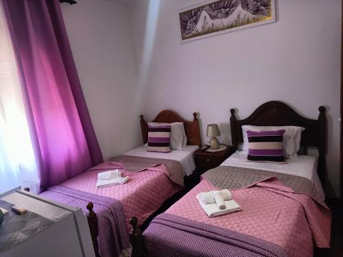 duas camas num quarto com lençóis rosa e roxo em Alojamento Local Largo da Igreja em Santiago do Cacém