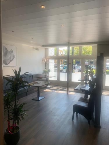 a lobby with tables and a chair and windows at Hotel Flevo in Zeewolde