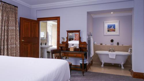 a bedroom with a bed and a tub and a sink at Glencoe House in Glencoe