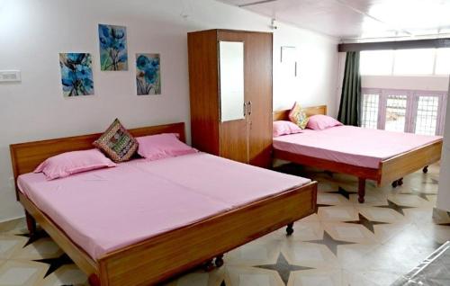 ムスーリーにあるBelleview Homestayのピンクのシーツが敷かれた部屋にベッドが2つ