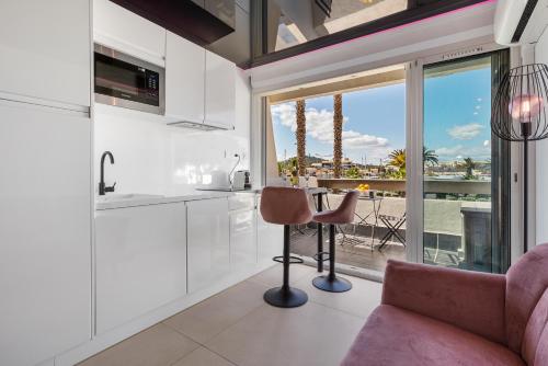 une cuisine avec des placards blancs et une table avec une chaise dans l'établissement Cabaret naturiste Port nature, au Cap d'Agde