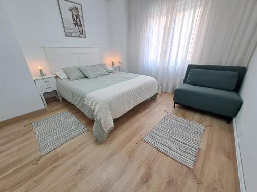 a bedroom with a bed and a green chair at Apartamento de 120m2 al lado de Cabarceno in Sarón
