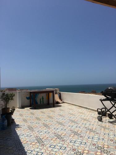 a patio with a table and a view of the ocean at EL Faro Surfstay in Tamri
