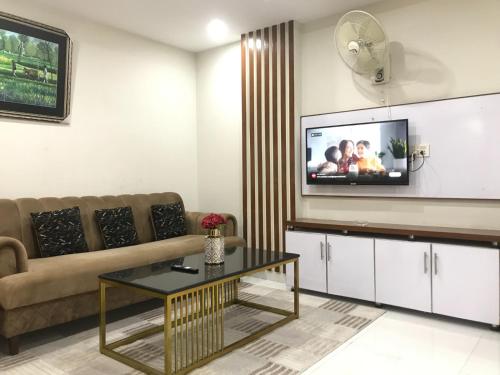 a living room with a couch and a tv on the wall at Mukhtar Homes Bahria Town Lahore in Lahore