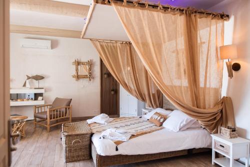 サン・ジルにあるAbri Cosy - Suite Romantiqueのベッドルーム1室(カーテン付きのベッド1台付)