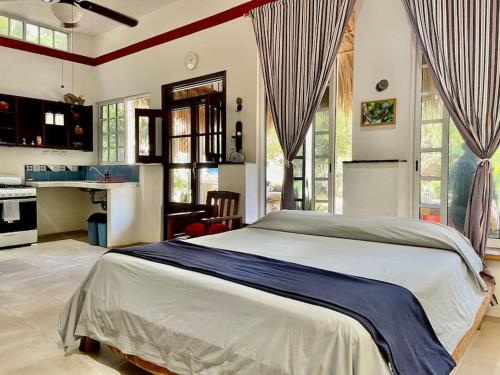 a bedroom with a large bed and a kitchen at Surrounded by Cenotes, Mayan sites and Haciendas in Seyé