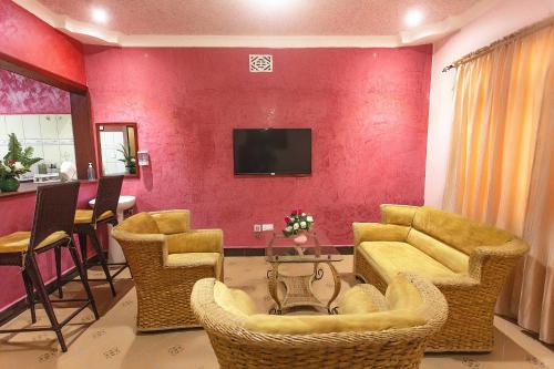 a living room with a couch and chairs and a tv at The Okaseni Lodge in Arusha