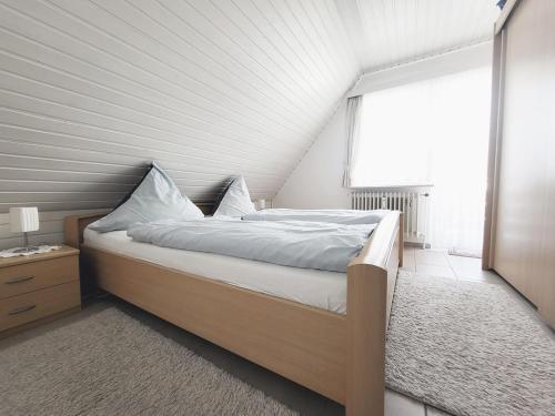 a white bedroom with a bed and a window at Friesenhain Ferienwohnungen in Sankt Peter-Ording