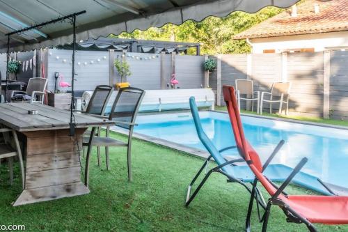 - une table et des chaises à côté de la piscine dans l'établissement Détente Piscine et jacuzzi au Bassin d'Arcachon, à Andernos-les-Bains