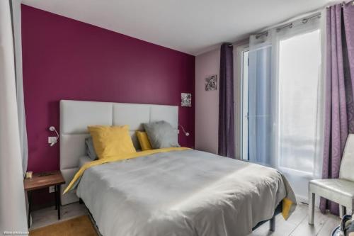 une chambre avec un grand lit et un mur violet dans l'établissement Détente Piscine et jacuzzi au Bassin d'Arcachon, à Andernos-les-Bains