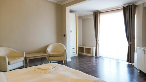 a bedroom with a bed and chairs and a window at Hotel Majestic in Durrës