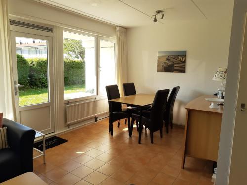 a dining room with a table and chairs and a window at ZON Bed by the Sea in Westkapelle