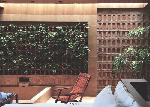 a chair in front of a wall with a plant at SANTI beach retreat in Ban Rang Pla