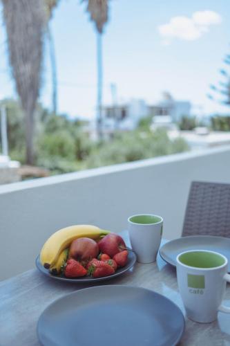 a plate of fruit on a table with two cups at Pavlos Place in Antiparos Town