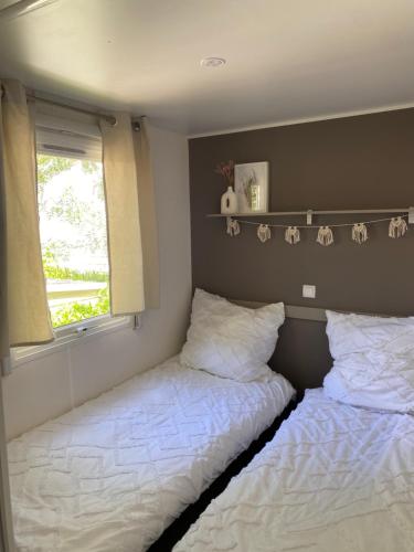2 camas individuales en una habitación con ventana en Ruhig gelegenes Mobilhome La Carabasse, en Vias