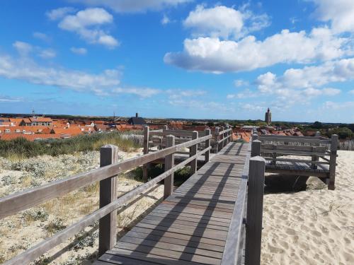 a wooden boardwalk on the beach with buildings in the background at ZON Bed by the Sea in Westkapelle