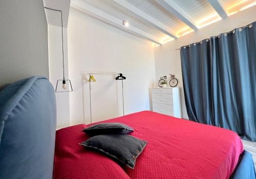 a bedroom with a red bed with black pillows on it at Rosalia Homestay - Ponente Apartment in Cinisi