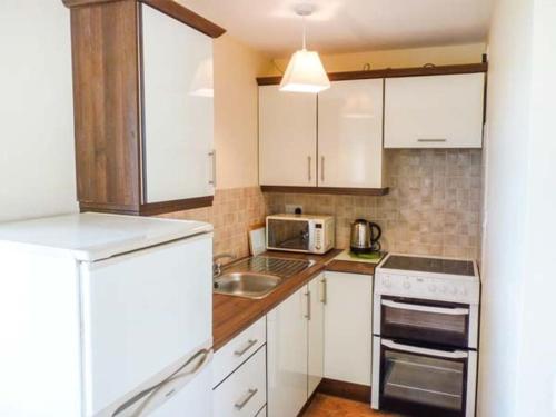 a small kitchen with white cabinets and a sink at The Getaway, Miltown Malbay in Miltown Malbay