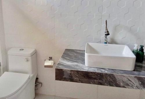 a white bathroom with a sink and a toilet at Jazz Ferme Inn Batuan Bohol in Batuan