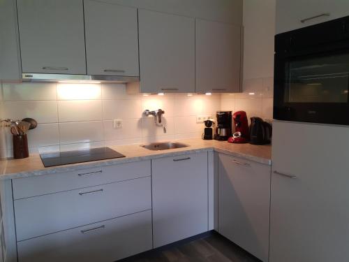 a kitchen with white cabinets and a sink at VUURTOREN Bed by the Sea in Westkapelle