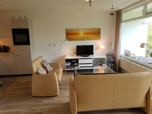 a living room with a couch and chairs and a tv at VUURTOREN Bed by the Sea in Westkapelle