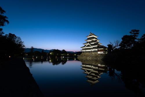 a chinese building on a lake at night at Popotel 2 NIKAI in Matsumoto