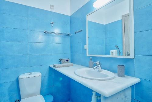a blue bathroom with a sink and a toilet at Pavlos Place in Antiparos Town