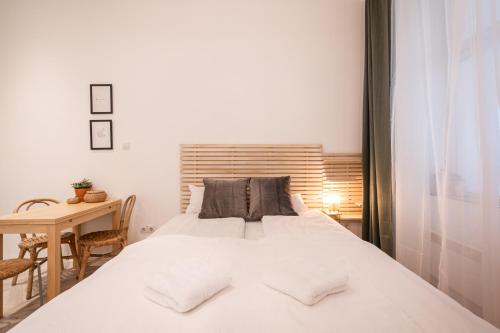 Un dormitorio con una gran cama blanca y una mesa en A20- Boutique Apartments, Best Location. By BQA, en Budapest