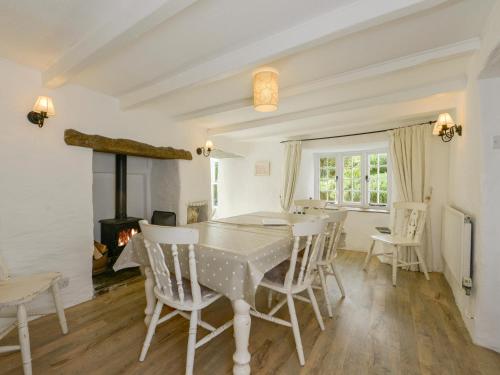 uma sala de jantar com uma mesa e cadeiras e uma lareira em Ayr Cottage em Tintagel